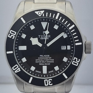 May include: A stainless steel Tudor Pelagos watch with a black dial and bezel. The watch features white hour markers, hands, and a date display. The bezel has white numerals and markers. Water-resistant to 500m (1640ft).