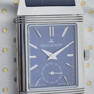 Pu&ograve; includere: Un orologio da polso rettangolare con quadrante blu e lancette argentate, con il logo Jaeger-LeCoultre. L'orologio ha una cassa argentata e un cinturino in pelle blu. Il quadrante include un piccolo quadrante dei secondi e la scritta "SWISS MADE".
