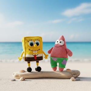 Könnte beinhalten: Gehäkelte Figuren von SpongeBob Schwammkopf und Patrick Star am Strand. SpongeBob ist gelb mit braunem Sockel, Patrick ist rosa mit grünen Shorts. Im Hintergrund sind Meer und Himmel zu sehen. Die Figuren stehen auf einem Stück Treibholz.