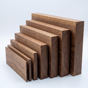 Puede incluir: Una colección de siete bloques de madera rectangulares de diferentes tamaños, dispuestos en un patrón escalonado. Los bloques son de un color marrón cálido intenso con vetas de madera visibles, lo que sugiere un material natural. La disposición crea una exhibición visual.