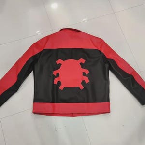 May include: Red and black jacket with a unique design. The jacket features a red upper section and sleeves, with a black central panel. A red emblem is centered on the back. The jacket has a classic collar and long sleeves.