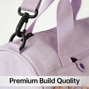 May include: Close-up of a lavender duffel bag with a black metal clasp and zipper. The bag has a matching lavender strap and the text "Premium Build Quality" is visible at the bottom.