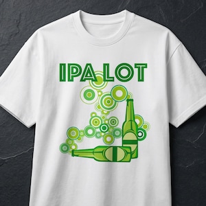 May include: White t-shirt with the text "IPA LOT" in green block letters. The design features green beer bottles and circular patterns in varying shades of green, creating a playful and eye-catching graphic.