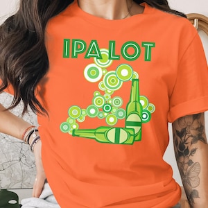 May include: Orange t-shirt with the text "IPA LOT" in green block letters. The shirt features a graphic of green beer bottles and circular designs in shades of green and white.