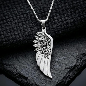 Silver angel wing pendant necklace with stainless steel chain displayed on a hand against a dark background, symbolic guardian angel jewelry and meaningful memorial gift.