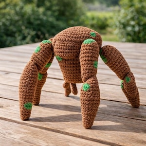 May include: A handmade brown crochet spider with six legs and green accents. The spider is sitting on a wooden surface, with a blurred green background. The crochet spider is a unique, whimsical item.