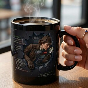 May include: Black ceramic coffee mug featuring a detective illustration with a magnifying glass, surrounded by code. The mug has a black handle and a steam rising from the top. The text on the mug reads "BUG HUNTING".