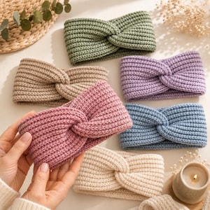 May include: A collection of six knitted headbands featuring a central twist design. The headbands are available in various solid colors including sage green, beige, lavender, dusty rose, light blue, and cream, all with a ribbed texture.