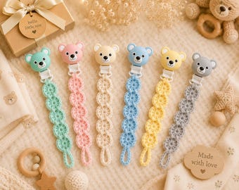 Puede incluir: Seis broches para chupete con cabezas de oso de plástico en colores menta, rosa, crema, azul, amarillo y gris. Cada broche tiene una correa larga de ganchillo hecha de motivos circulares conectados, terminando en un pequeño lazo.