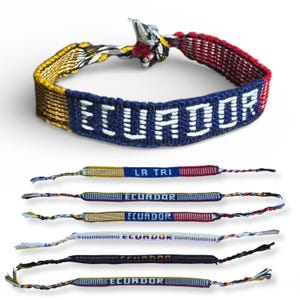 May include: Woven bracelets featuring the word "ECUADOR" in white on a blue band. The bracelets have yellow, red, and blue woven patterns. Additional bracelets with "LA TRI" and "ECUADOR" are also visible.