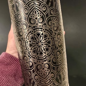 May include: A stainless steel tumbler with a black and silver mandala design. The design includes the phrases "THIS IS BULLSHIT", "FUCK THAT", and "FUCK OFF". The tumbler is cylindrical and has a silver base.