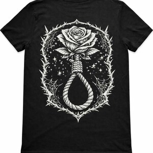 May include: Black t-shirt featuring a detailed white graphic. The design includes a rose, a noose, thorns, and spiderwebs, set against a starry background. The artwork has a gothic or alternative aesthetic.