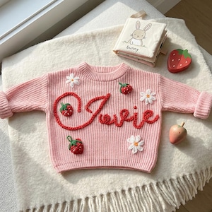 Könnte beinhalten: Handgefertigtes Holzschild mit dem Wort "Welcome" in verspielter Schrift. Das Schild hat einen weißen, abgenutzten Hintergrund und einen dunkel gebeizten Holzrahmen, ideal für einen Hauch von rustikalem Charme.