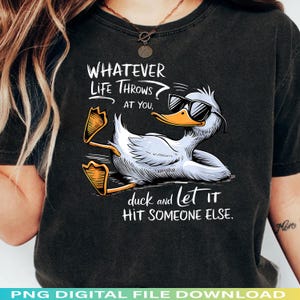 May include: Black t-shirt featuring a cartoon duck wearing sunglasses. The duck is lying down with its feet up, and the text reads "WHATEVER LIFE THROWS AT YOU, duck and let it HIT SOMEONE ELSE."