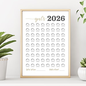May include: A framed print with a gold border, featuring the text "goals 2026" in gold and black. The print has a grid of small house icons, with spaces for "Sales Volume" and "Units closed" at the bottom.