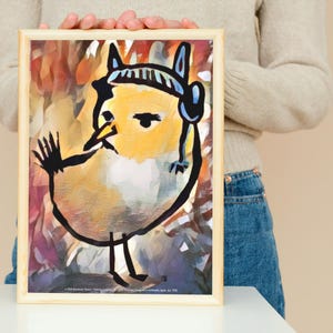以下が含まれることがあります： 真剣な表情の気まぐれな漫画の鳥が描かれた額入りのアートプリント。鳥は主に黄色で、黒いアウトラインと青のアクセントがあります。アートワークは、カラフルな抽象的な背景に対して、テクスチャード加工された絵画風のスタイルです。