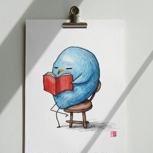 以下が含まれることがあります： 小さな木製の椅子に座り、赤い本を読む青い鳥の気まぐれなイラスト。アートワークは金属製のクリップで白い表面に固定されています。画像の下部にテキストが含まれています。