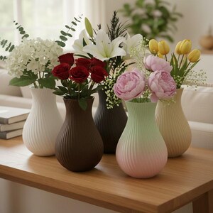 May include: Five decorative vases of different colours and shapes, each filled with fresh flowers. The vases are arranged on a wooden table, showcasing a variety of floral arrangements, including roses, lilies, and tulips.