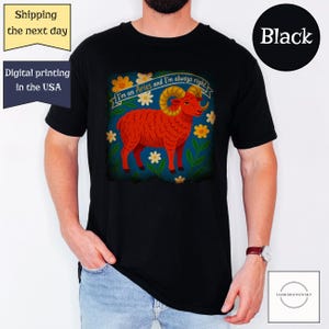 May include: Black t-shirt featuring a vibrant illustration of a red ram with golden horns, surrounded by flowers and the text "I'm an Aries and I'm always right." The shirt is a classic crew neck style.