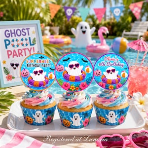 May include: Three cupcakes in blue wrappers with ghost and hibiscus prints, topped with swirled frosting and circular toppers. The toppers feature a ghost in sunglasses floating in a pool ring with text reading Summerween Birthday Party and Olivia's 8th Birthday.