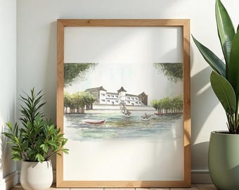 May include: Watercolor painting of a building on a lake, framed in light wood. The artwork depicts a white building with a dark roof, surrounded by trees and boats. The water is a mix of blues and greens.