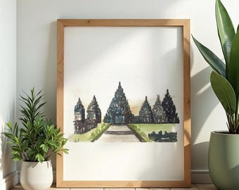 May include: Watercolor painting of a temple complex in shades of gray, brown, and green, framed in light wood. The artwork is displayed on a white wall, with potted plants on the floor. The painting depicts a path leading to the temple.