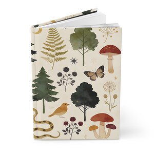 May include: A hardcover journal with a cream-colored background and a whimsical forest design. The cover features illustrations of trees, mushrooms, a snake, a bird, and a butterfly in shades of green, brown, and orange.