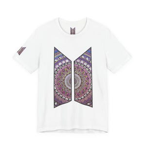 Könnte beinhalten: Weißes T-Shirt mit einem farbenfrohen Mandala-Design in einer stilisierten geometrischen Form. Das Design verwendet Lila-, Rosa- und Blautöne. Ein kleines Logo ist auch auf dem Ärmel und am Ausschnitt zu sehen.
