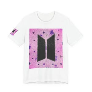 Könnte beinhalten: Weißes T-Shirt mit einem großen schwarzen Grafikdesign auf der Vorderseite. Das Design ist ein stilisiertes Logo mit einem rosa und lila Hintergrund mit kleinen Herzen. Auf dem Ärmel befindet sich eine kleine Grafik.