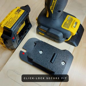 May include: A black and yellow power tool battery charger and a black adapter with the text "CLICK-LOCK SECURE FIT". The charger and adapter are on a light brown surface. The power tool is black and yellow.