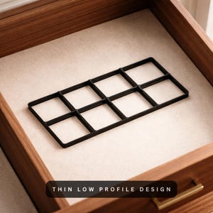 May include: A black, grid-like organizer sits inside a wooden drawer with a beige interior. The organizer has eight square compartments. The text "THIN LOW PROFILE DESIGN" is displayed at the bottom of the image.