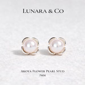 May include: A pair of Akoya flower pearl stud earrings featuring a 7mm white pearl centered within a silver-toned metal setting shaped like four rounded petals. The text LUNARA & CO and AKOYA FLOWER PEARL STUD 7MM is visible in the image.