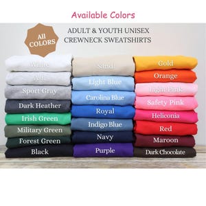 May include: A display of folded adult and youth unisex crewneck sweatshirts in various colors, including white, black, and red. The image includes text that reads "Available Colors" and "All Colors".