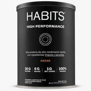 May include: A black cylindrical container of HABITS High Performance protein powder. The label includes the text "CACAO", "30G PROTEIN", "6G BCAAS", "1G NET CARBS", and "100% VEGAN". The container also states it is a plant-based protein supplement.