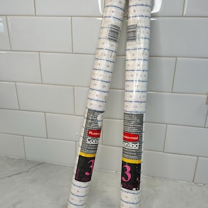 May include: Two rolls of floral patterned contact paper. The paper has a white background with a repeating pattern of small pink flowers and blue ribbon-like designs. The rolls are labeled with the brand name and the number "3".