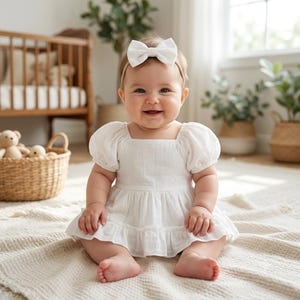 White eyelet baby girl dress romper with bow headband. Elegant blessing garment and flower girl outfit for infant dedication ceremony.