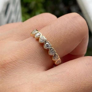 Könnte beinhalten: Eine weiße Keramik-Tasse mit schwarzem Henkel und dem Text "But First, Coffee" in fetter, schwarzer Schrift. Die Tasse steht vor einem verschwommenen Hintergrund, der eine gemütliche Umgebung suggeriert.