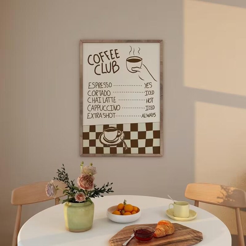 May include: A rectangular wall art print titled COFFEE CLUB with a menu listing espresso, cortado, chai latte, cappuccino, and extra shot. The design features a hand holding a cup and a brown and white checkered pattern at the bottom.