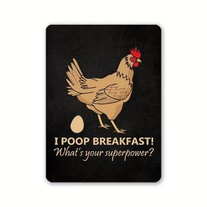 May include: A rectangular black sign with a cartoon chicken, egg, and text. The chicken is brown with a red comb. The text reads "I POOP BREAKFAST! What's your superpower?"