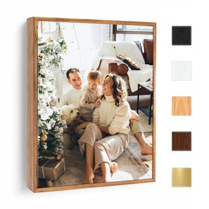 May include: A framed family photo with a wooden frame. The photo shows a family of three and a dog, sitting in front of a Christmas tree. The frame is available in multiple colors, including black, white, light wood, dark wood, and gold.