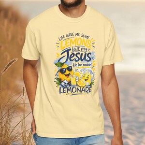 Man wearing Christian lemon shirt with “Life Gave Me Some Lemons But My Jesus He Be Makin’ Lemonade” graphic featuring cute lemon characters and faith message.