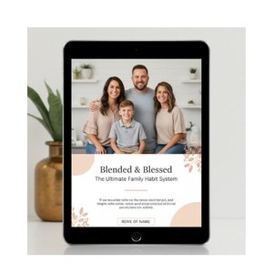 以下が含まれることがあります： 黒いタブレットには、家族の肖像画と「Blended & Blessed: The Ultimate Family Habit System」というテキストが表示されています。タブレットは、背景に金色の花瓶と植物がある白い表面にあります。