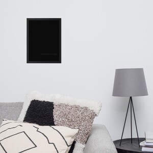 May include: A framed black art print with a minimalist design. The print features a solid black background with a line of white text at the bottom. The frame is black and rectangular.