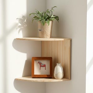 May include: A light-coloured wooden corner shelf with two tiers, featuring a potted plant, framed artwork of a red horse, and a small white vase. The plant pot has the word "Sage" on it.