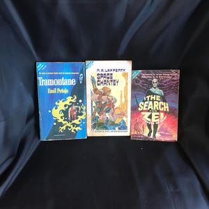 Może przedstawiać: Trzy książki w miękkiej oprawie science fiction w stylu vintage. Tytuły to „Tramontane” Emila Petaji, „Space Chanty” R.A. Lafferty'ego i „The Search for Zel”. Książki mają kolorowe okładki z ilustracjami i tekstem.