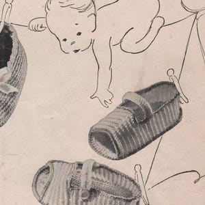 Puede incluir: Tres botines de bebé de ganchillo con una correa y cierre de botón. Los botines están colgados de una cuerda para tender la ropa con pinzas.