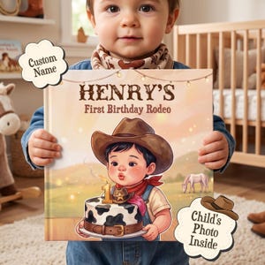 Op de afbeelding: Een vierkant hardcover boek getiteld Henry's First Birthday Rodeo met een illustratie van een kind met een cowboyhoed dat een kaarsje uitblaast op een taart met koeienvlekken. De kaft bevat lichtsnoeren en een afbeelding van een paard.