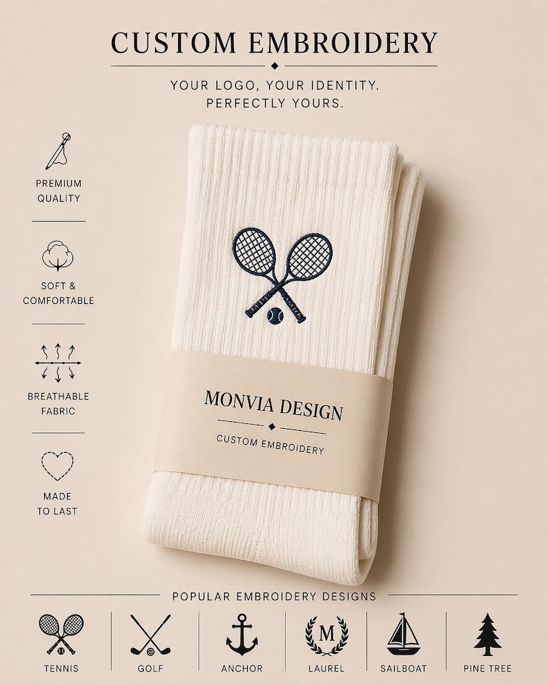 Puede incluir: Calcetines acanalados de color blanco roto con un bordado azul oscuro de dos raquetas de tenis y una pelota. Una banda de papel con la etiqueta MONVIA DESIGN CUSTOM EMBROIDERY envuelve el centro. La imagen incluye iconos de caracter&iacute;sticas.
