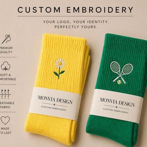 Puede incluir: Un par de calcetines acanalados, uno amarillo con un bordado de margarita blanca y otro verde con un bordado de raquetas de tenis y una pelota. Cada par est&aacute; envuelto en una banda de papel MONVIA DESIGN CUSTOM EMBROIDERY. El texto incluye CUSTOM EMBROIDERY, YOUR LOGO, YOUR IDENTITY, PERFECTLY YOURS, PREMIUM QUALITY, SOFT & COMFORTABLE, BREATHABLE FABRIC y MADE TO LAST.