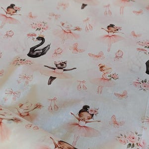 Peut inclure: Tissu crème avec un motif répété de ballerines en tutus roses, de cygnes noirs, de papillons et de bouquets de fleurs. Le motif comprend des chaussons de ballet et des nœuds, créant une esthétique fantaisiste et délicate.